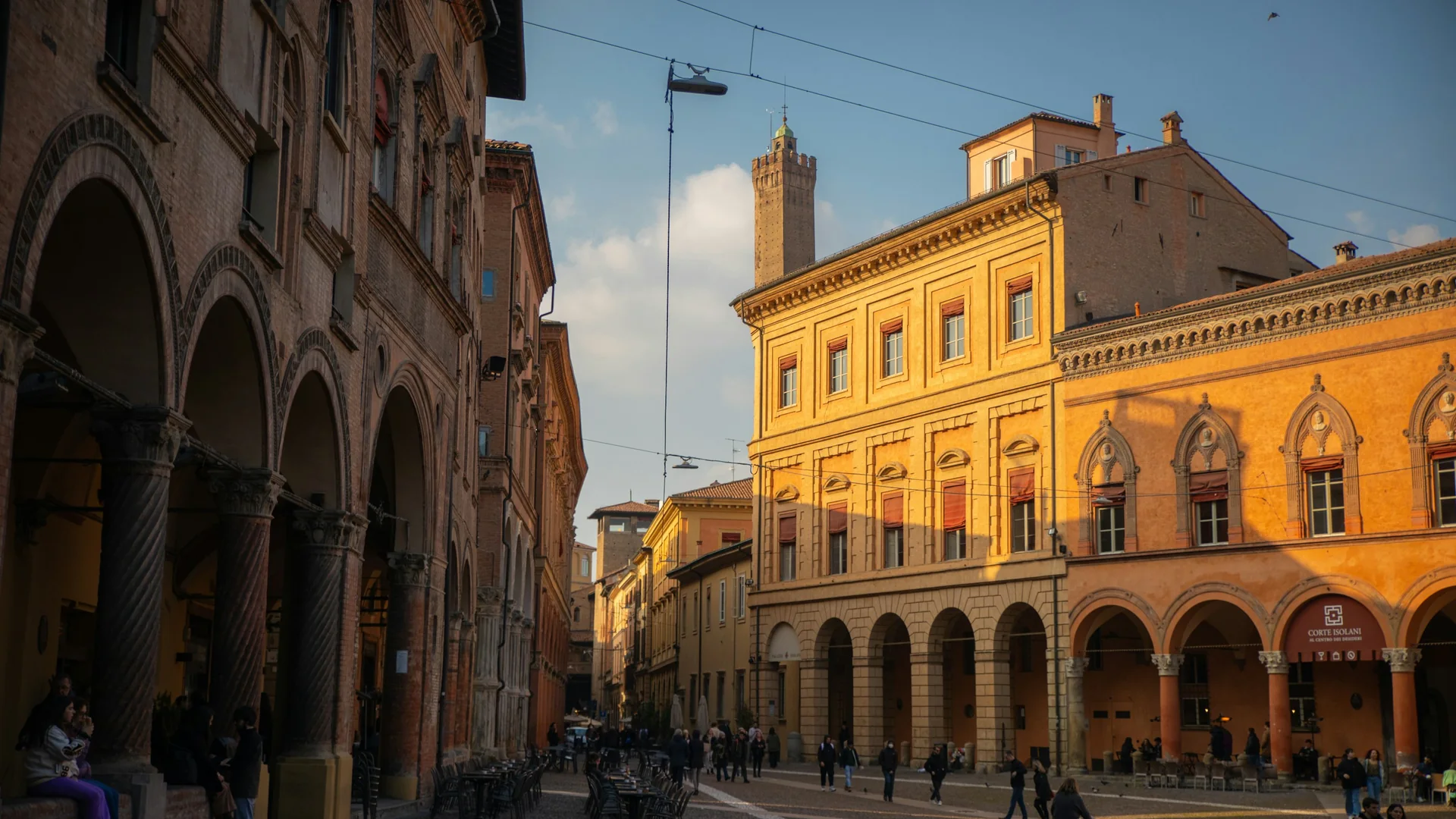 Late sun on the ochre and terracotta palazzi and arcaded streets of old Bologna, with a brick tower rising over the rooftops